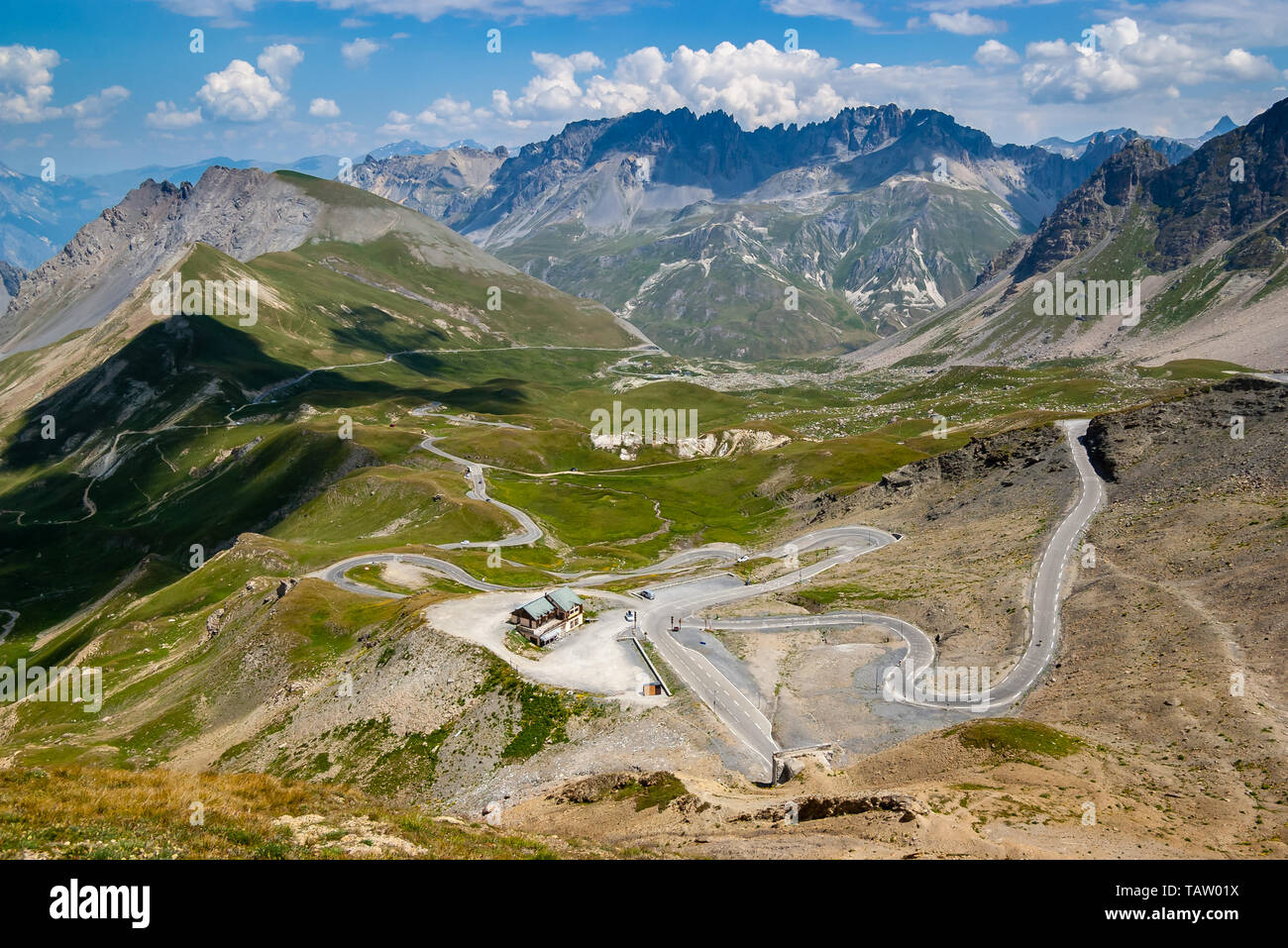 Panorama dalla cima di una montagna passare Col du Galibier. Alpine strada a serpentina, avvolgimento in una verde vallata alpina circondata da imponenti montagne. Foto Stock