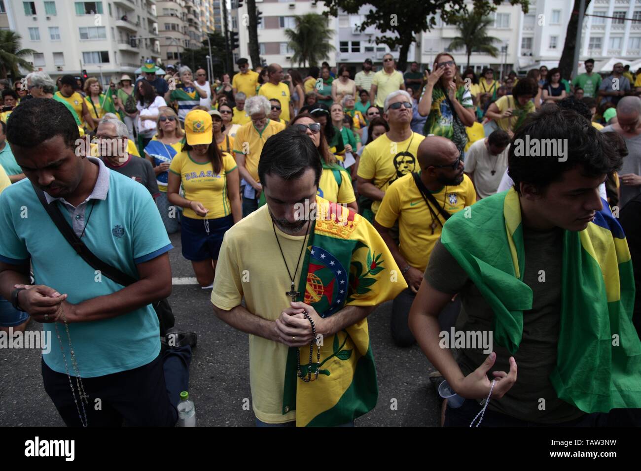 Rio De Janeiro, Brasile. 26 Maggio, 2019. Christian i sostenitori del Presidente Jair Bolsonaro pregare nel corso di una manifestazione organizzata questa domenica sulla spiaggia di Copacabana, a sud di Rio de Janeiro in Brasile. Un uomo (al centro) porta il vecchio brasiliano bandiera imperiale del XVIII secolo. Credito: Ian Cheibub/dpa/Alamy Live News Foto Stock