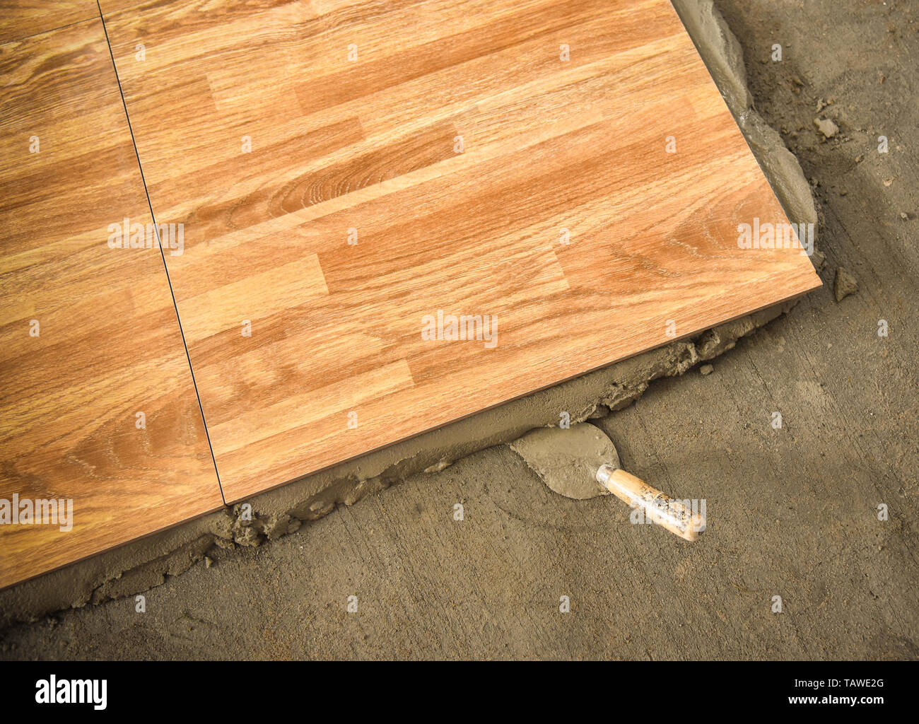 Installare il pavimento di piastrelle di malta di cemento rinforzato /  pavimento in cemento con cazzuola mescolatore di cemento per la costruzione  colla sul terreno Foto stock - Alamy