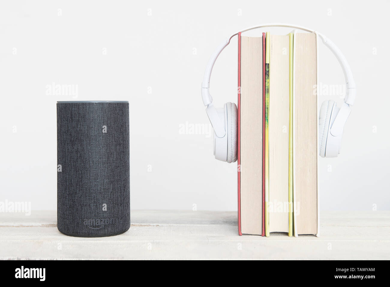 Smart speaker Amazon Alexa dispositivo eco sulla sinistra accanto ad alcuni libri e hearphones contro uno sfondo bianco. Svuotare lo spazio di copia per l'editor di testo Foto Stock