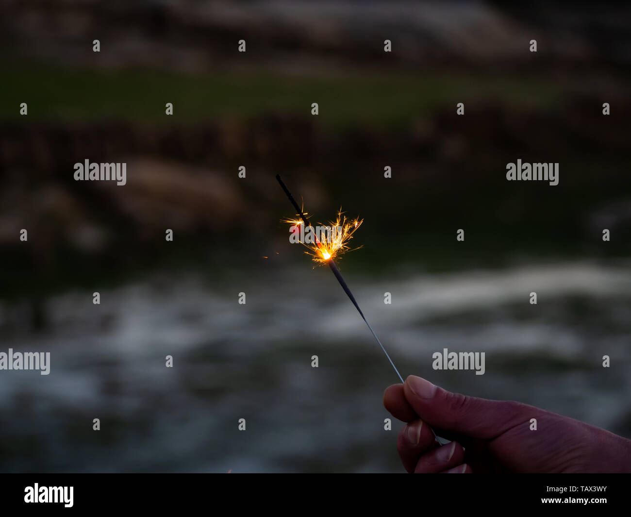 Un irriconoscibile persona con un sparkler sfrigolanti in mano Foto Stock