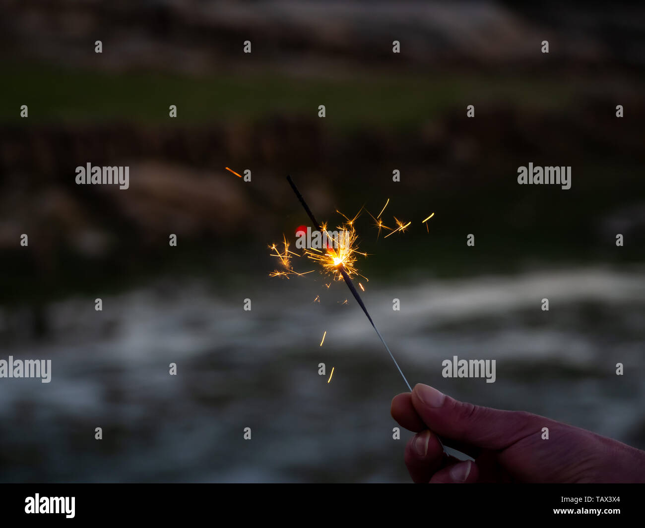 Un irriconoscibile persona con un sparkler sfrigolanti in mano Foto Stock