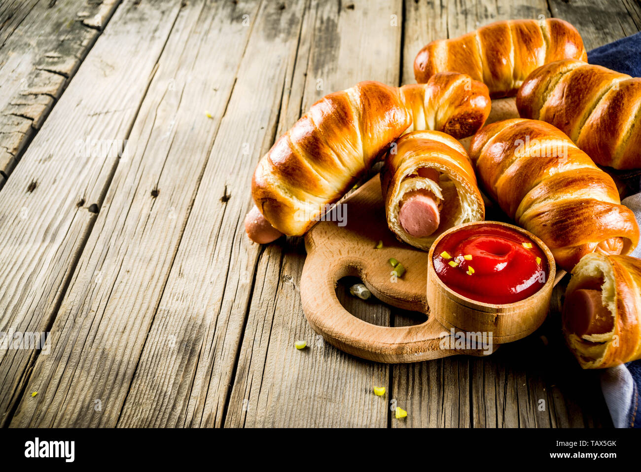 Pretzel avvolto hot dogs con salsicce, con ketchup salsa, sfondo scuro spazio copia Foto Stock