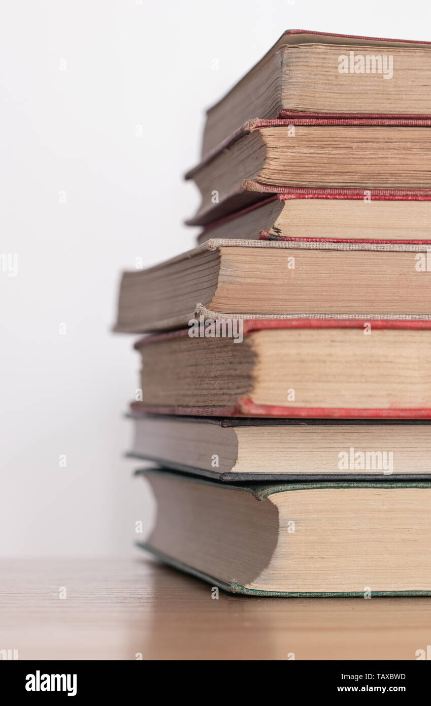 Pila di vecchi libri polverosi su una superficie in legno Foto Stock