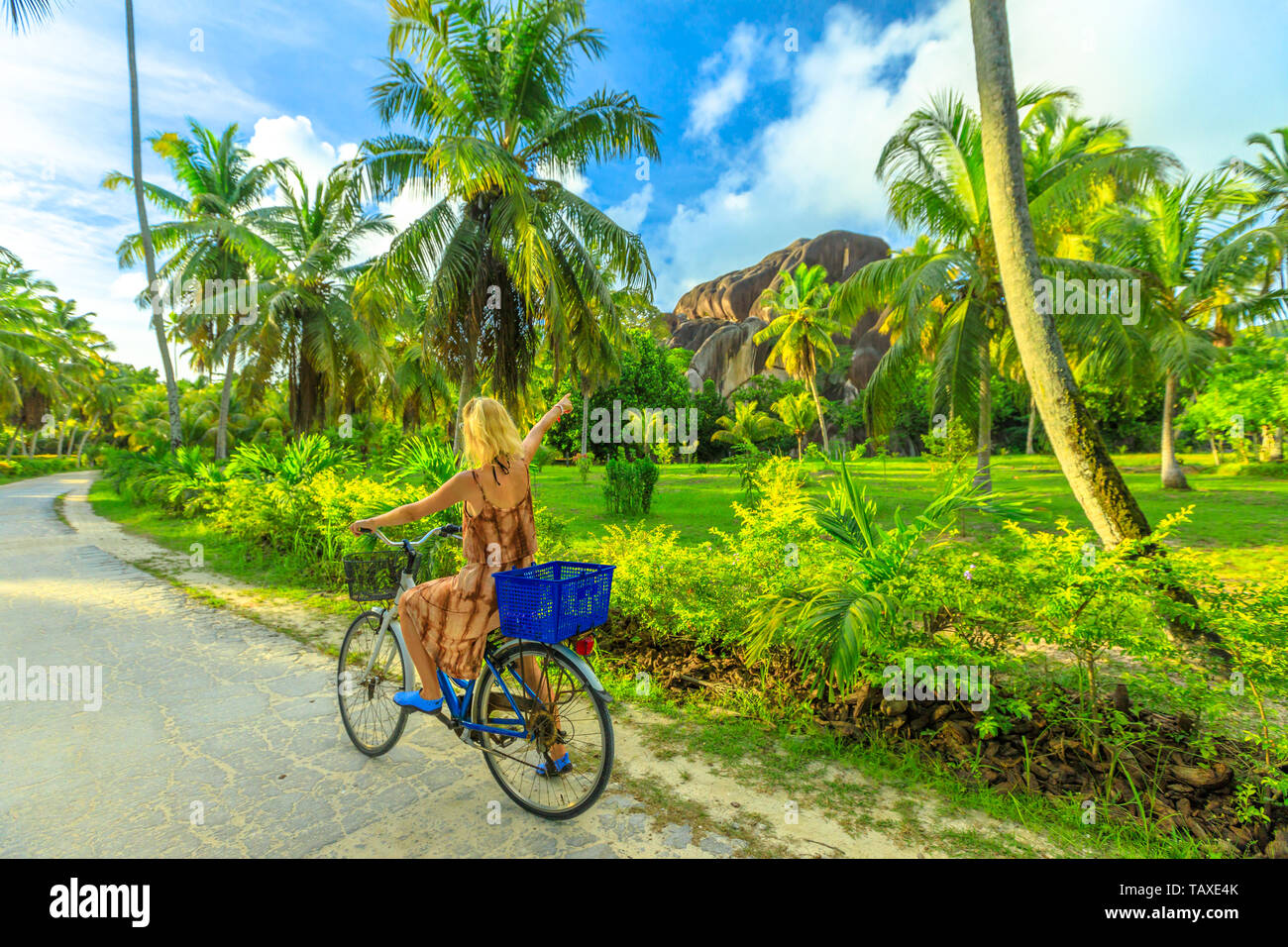 La Digue, Seychelles. Donna turistica sulla bicicletta gigante appuntita Unione Rock, un monolito presso la Union Station Wagon un ex cocco e vaniglia piantagione nei pressi di Anse Foto Stock