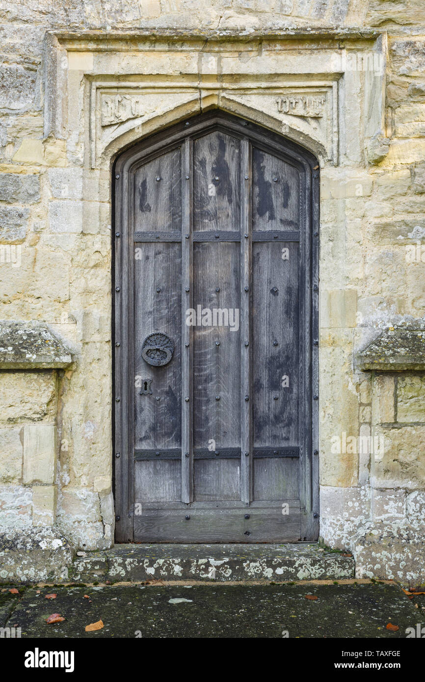 Arcuata antica porta di legno in entrata di un antico borgo medievale chiesa di pietra in Inghilterra Foto Stock