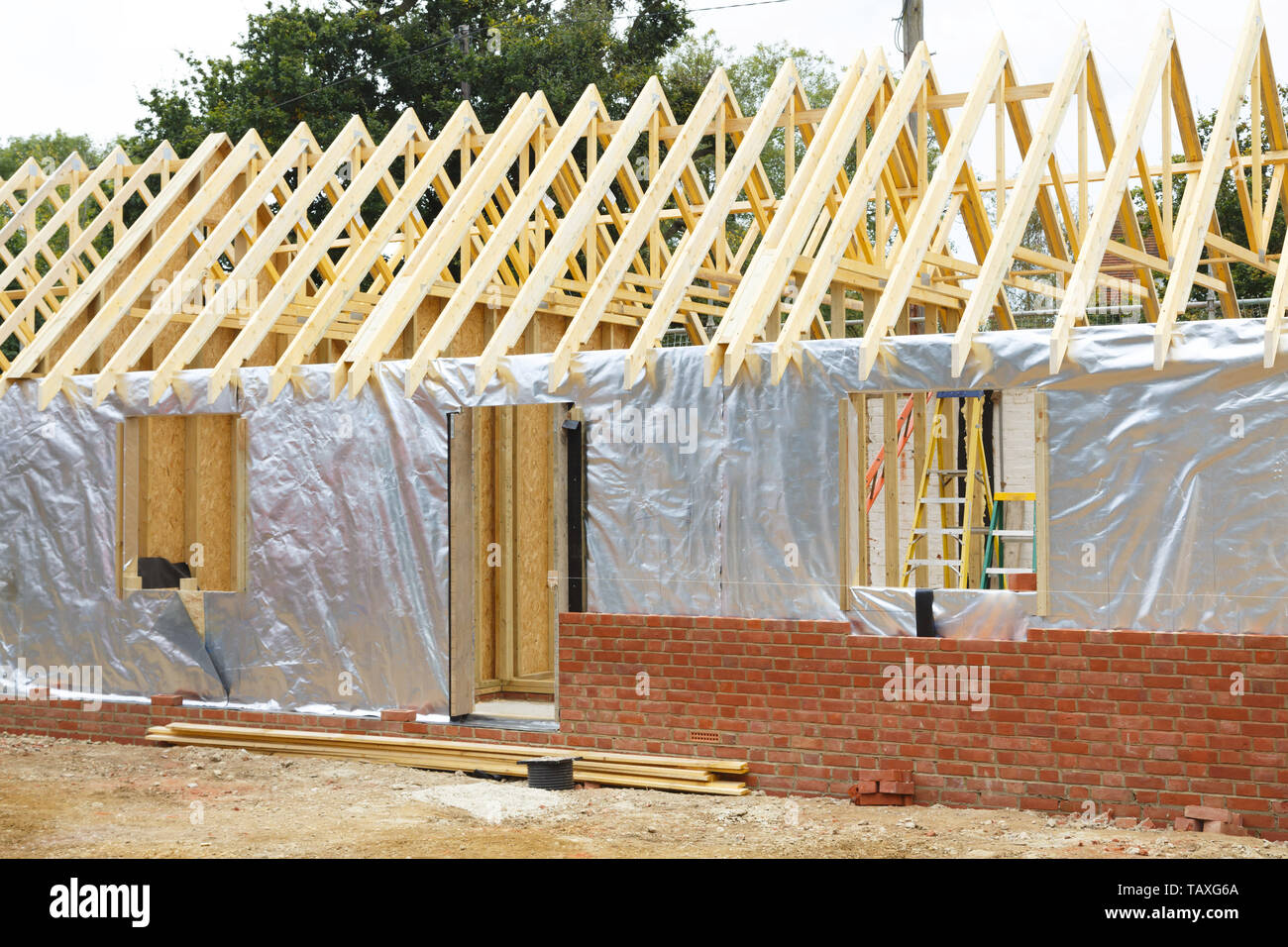 Casa con struttura in legno interno o allegato in costruzione con lamina di moderno e di isolamento esterno muro di mattoni Foto Stock