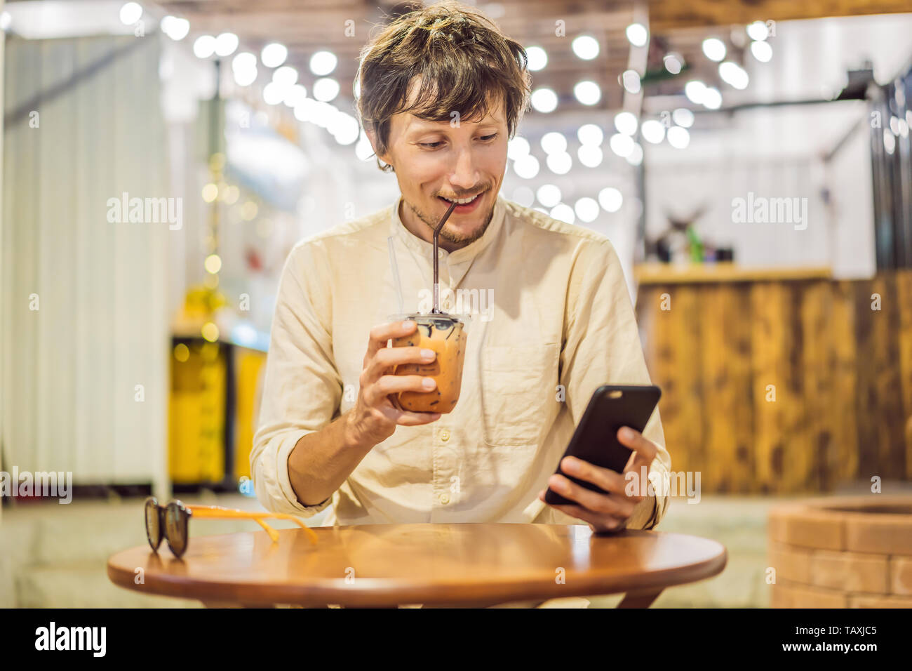 Uomo di bere freddo tè bolla in cafe Foto Stock