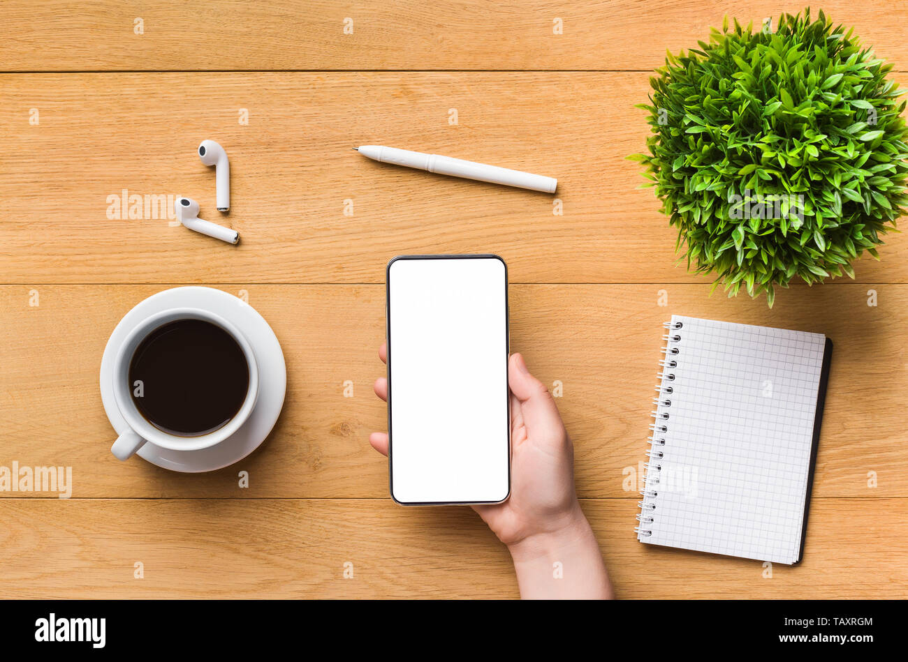 Telefono cellulare con schermo vuoto nella donna la mano sul posto di lavoro Foto Stock