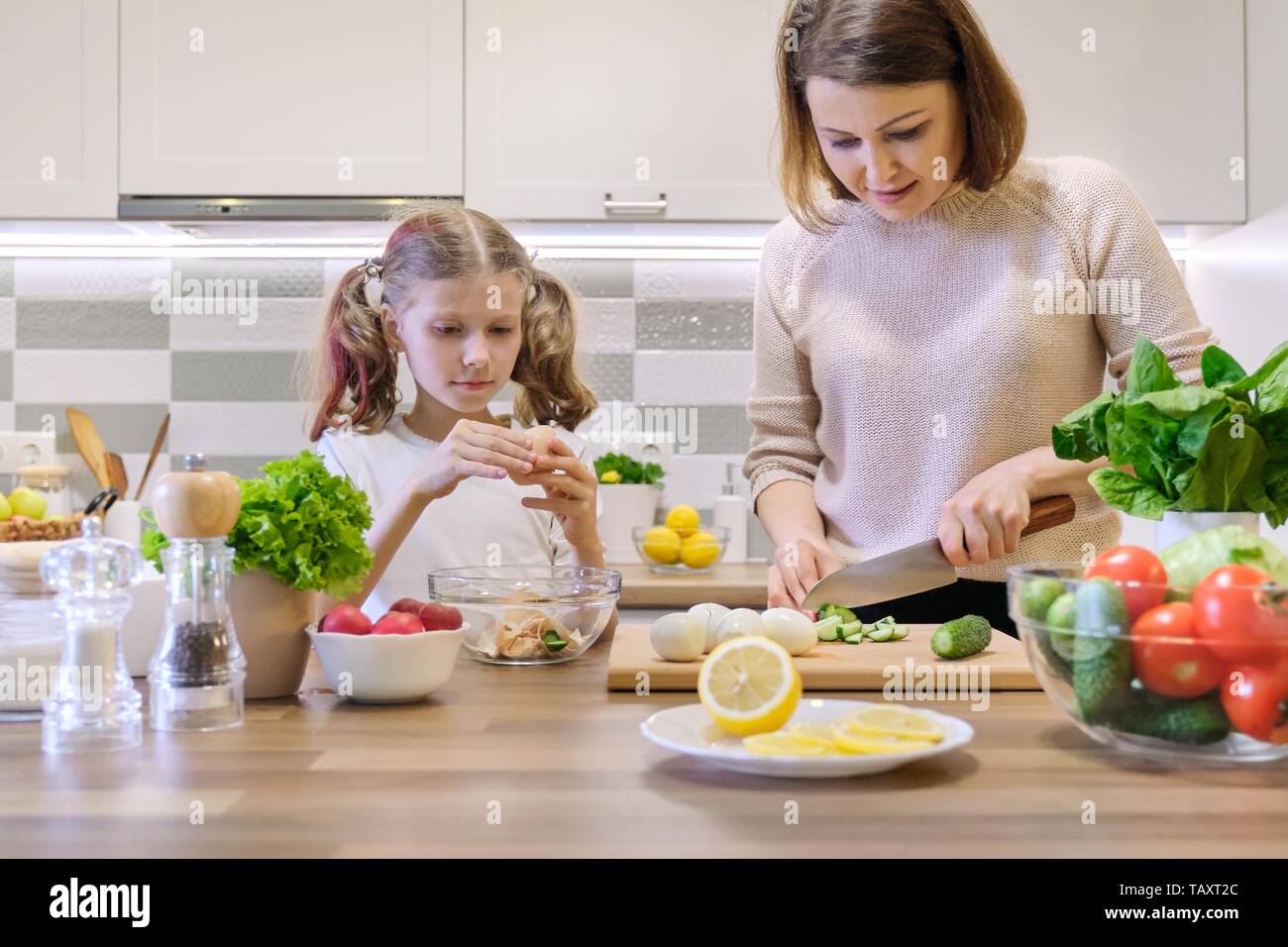 La madre e il bambino la cucina insieme a casa in cucina. Mangiare sano, madre figlia insegna a cucinare, genitore bambino comunicazione. Donna cucum di taglio Foto Stock