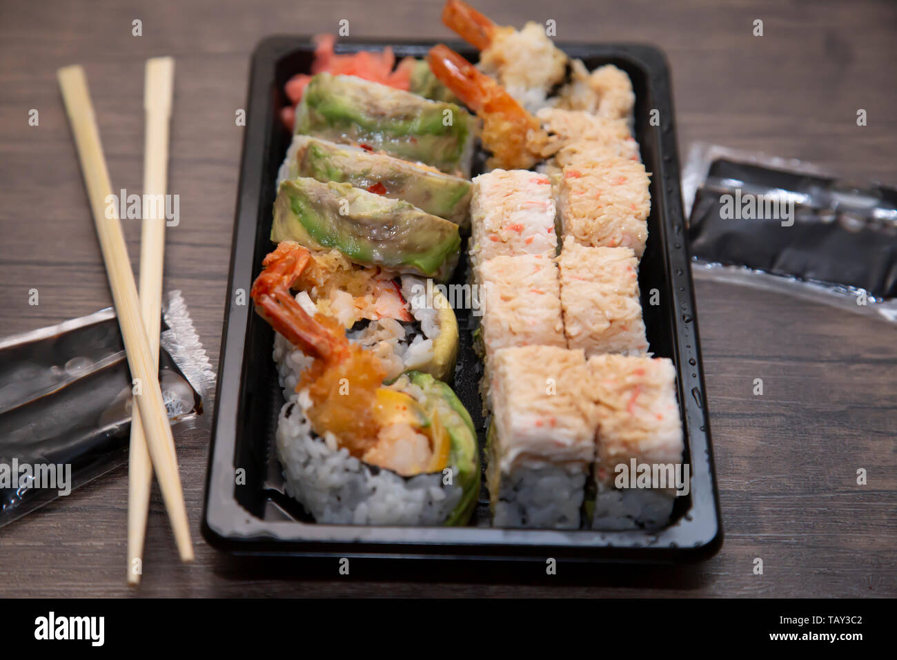 In prossimità dei rulli di sushi con polpa di granchio, avocado e gamberi, con bacchette e salsa di soia per lato Foto Stock