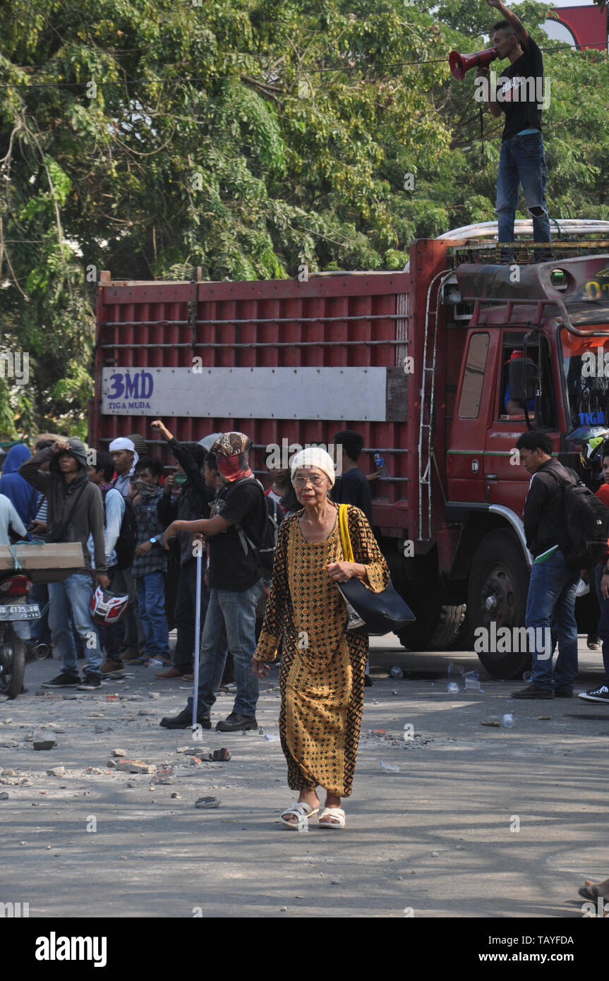 Una donna cammina vicino agli studenti rally di fronte Muhammadiah University a Allaudin Street. Gli studenti universitari in tutta l'Indonesia tenere street rally a c Foto Stock