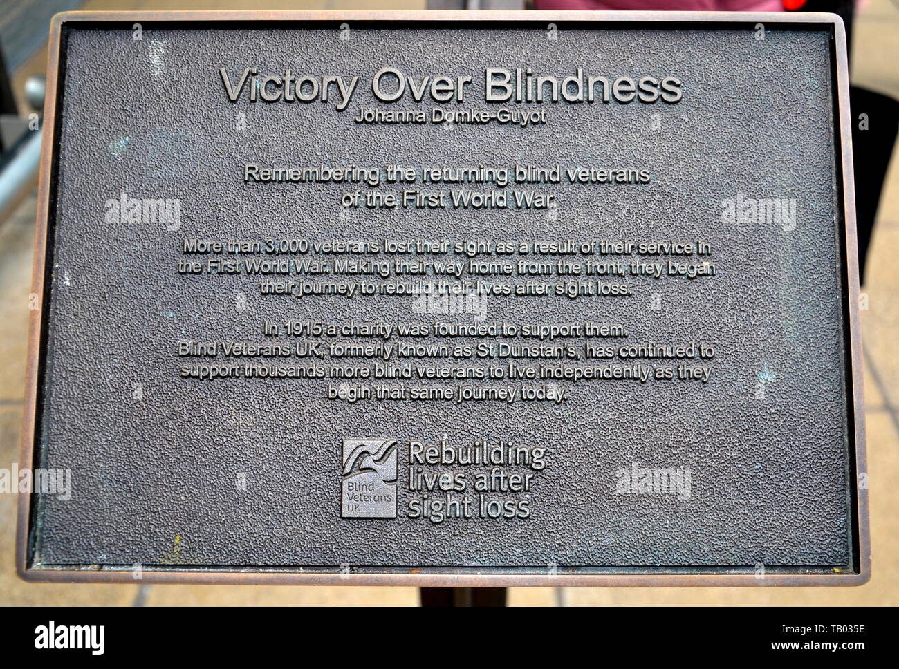 Il bando di gara che descrive la statua di sette soldati cieco - vittoria sulla cecità - all'ingresso della stazione ferroviaria di Manchester Piccadilly, Regno Unito Foto Stock