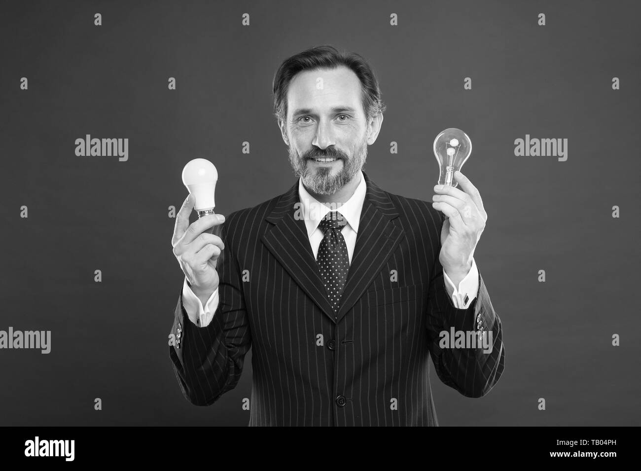 In cerca di nuove idee. La modalità di risparmio energetico. Maschio in abito di business. Imprenditore nel soddisfare tenere la lampada della luce. Di elettricità e di energia. Uomo con barba ricerca di ispirazione. Maturo uomo barbuto con lampada. Foto Stock