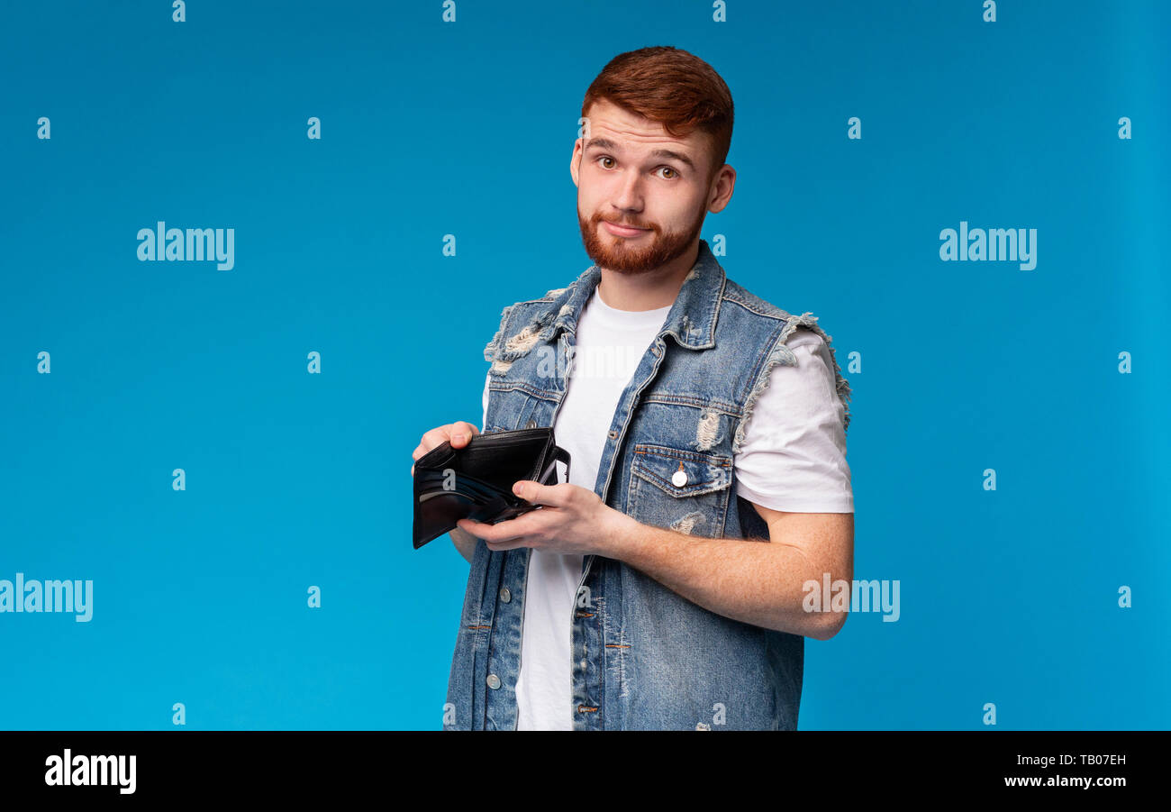 Triste uomo millenario che mostra il suo portafoglio vuoto alla fotocamera Foto Stock