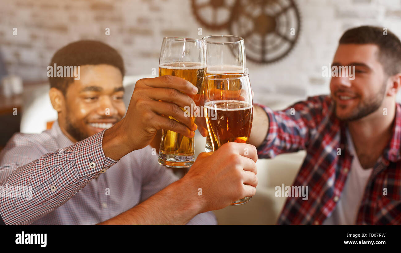 Happy amici tintinnanti bicchieri da birra, celebrando la riunione Foto Stock