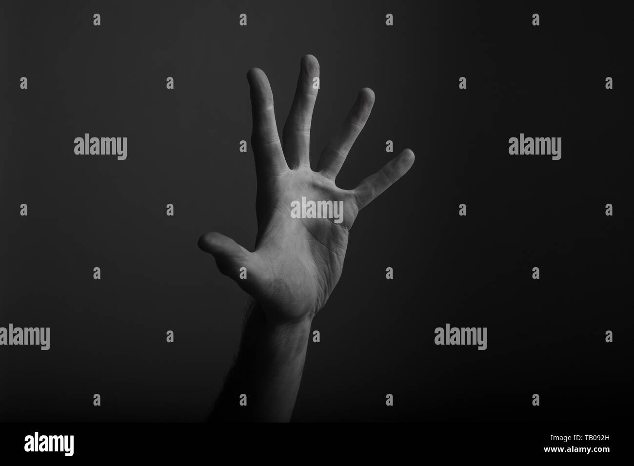 Maschio a mano aperta gesto su uno sfondo scuro Foto Stock