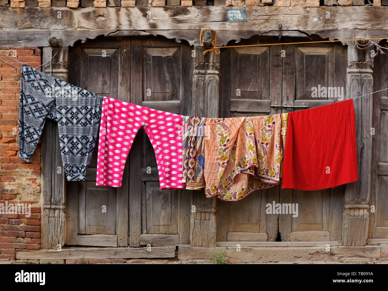 Coloratissimo Servizio lavanderia Asciuga sulla linea fuori Newari in mattoni e legno costruendo, old town Dhulikhel, Nepal Foto Stock
