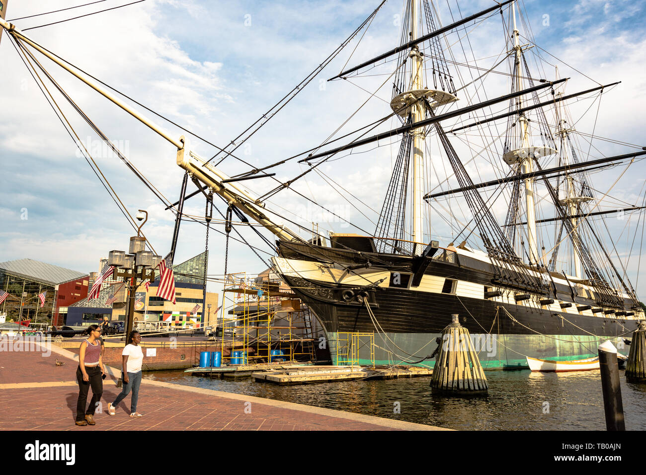 Baltimore, Maryland, Stati Uniti d'America - Luglio 11, 2017: Due ragazze a piedi passato la USS Constellation, uno degli storici navi ancorate in del Baltimore Inner Harbor. Bui Foto Stock