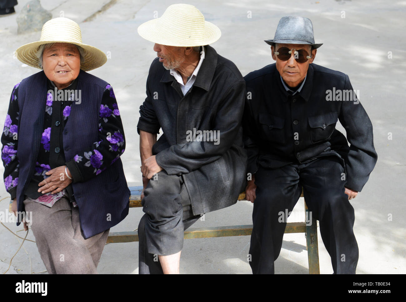 Anziani la popolazione cinese seduto su una panca in legno. Foto Stock