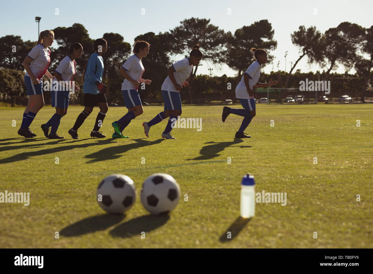 Team di giocatori di calcio in esecuzione in una linea sul campo sportivo Foto Stock