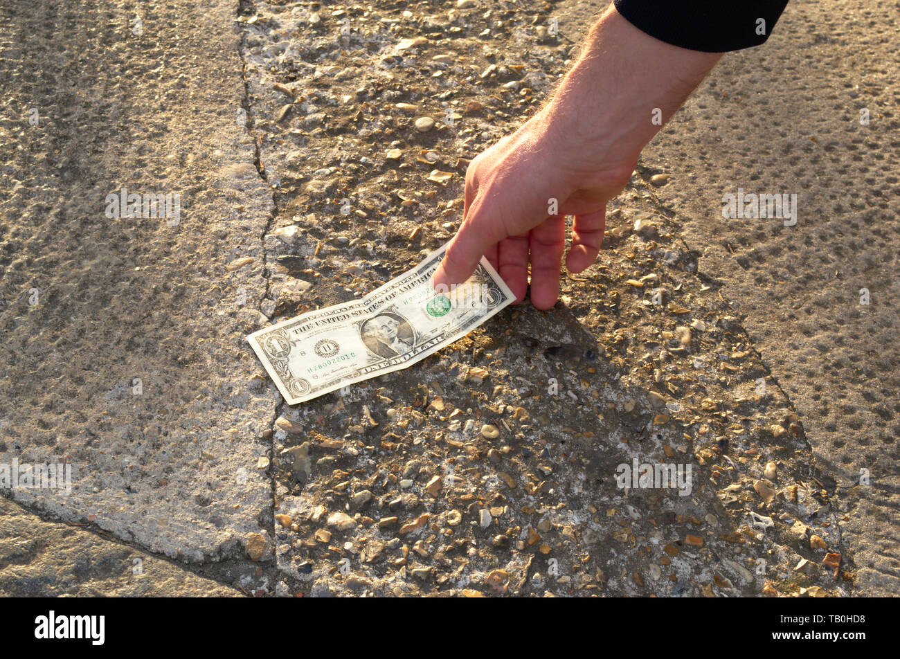 L'uomo fortunato è trovare il denaro per la strada sul pavimento. La persona fortunata ha trovato venti dollari. Una possibilità per una scommessa. Jackpot. Casino. Foto Stock
