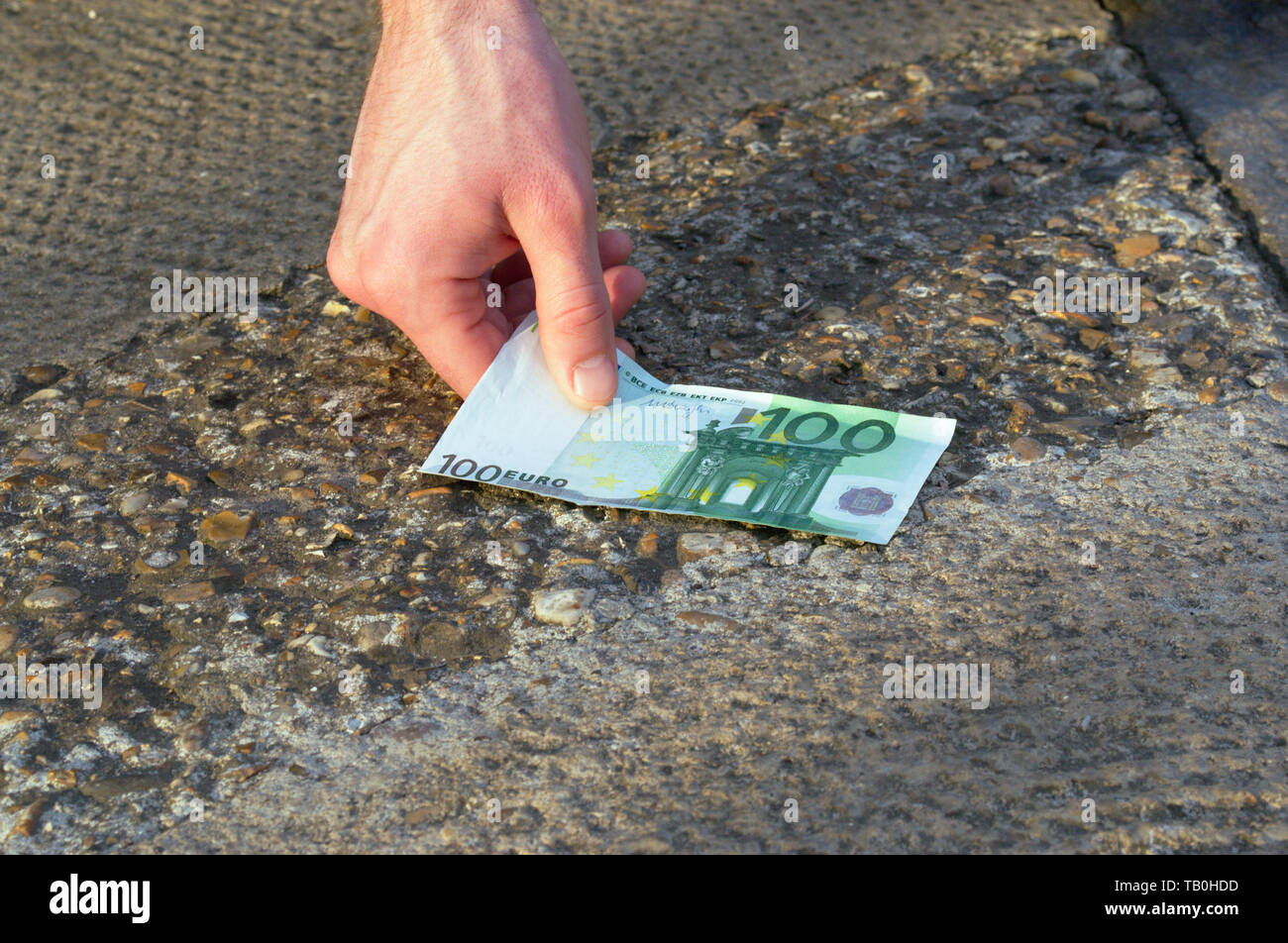 L'uomo fortunato è trovare il denaro per la strada sul pavimento. La fortunata persona ha trovato un centinaio di euro. Una possibilità per una scommessa. Jackpot. Casino. Foto Stock