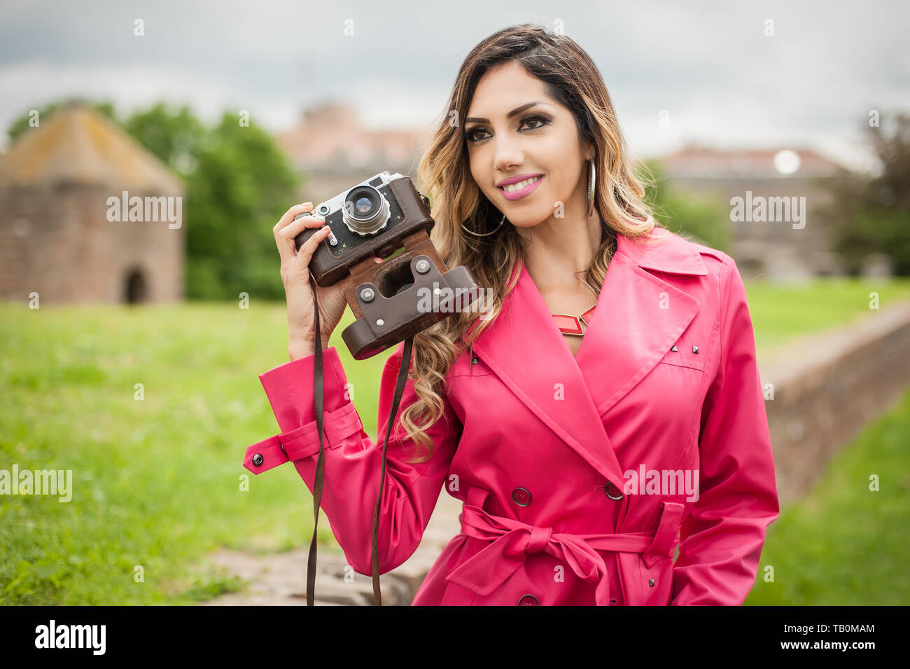 Bella giovane donna fotografa con pellicola vintage fotocamera sulla strada di città Foto Stock