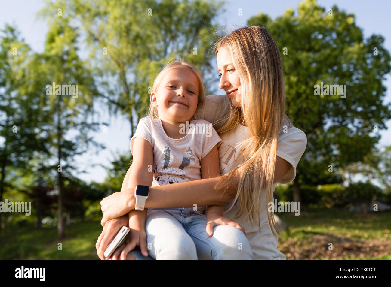 Bella giovane donna e bambina con capelli biondi all'aperto. Elegante ragazza camminare nel parco Foto Stock