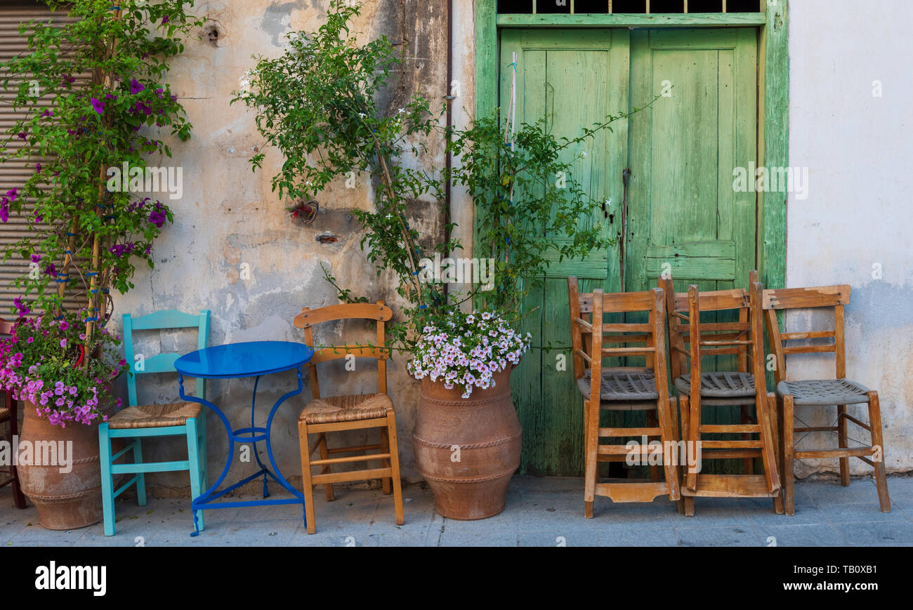 Sedie impilate fuori Greek street cafe, agio Nikolaos, Creta Foto Stock