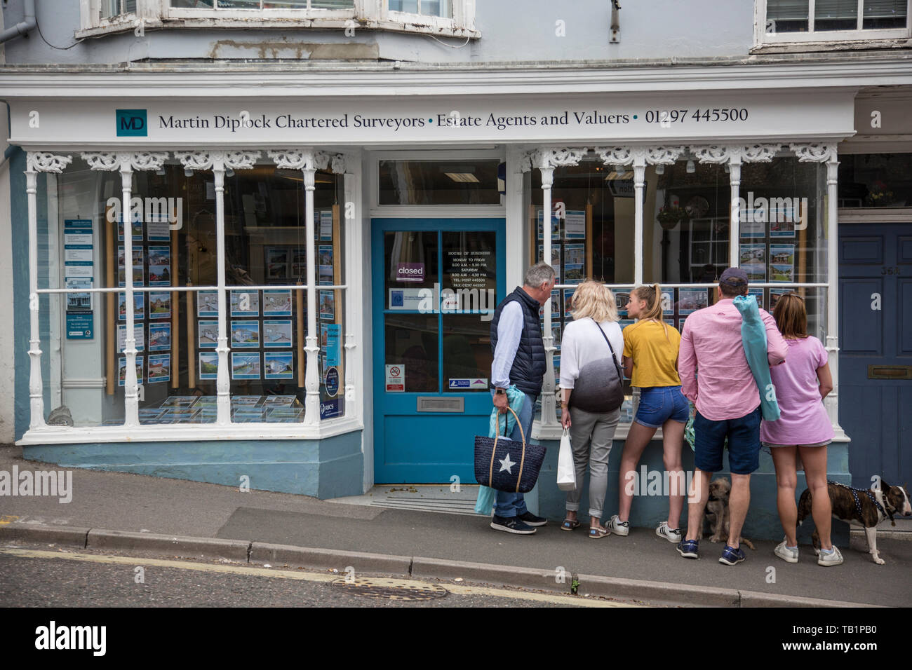 Famiglia guardando le proprietà per la vendita pubblicizzato in un agente immobiliare finestra nel West Dorset, England, Regno Unito Foto Stock