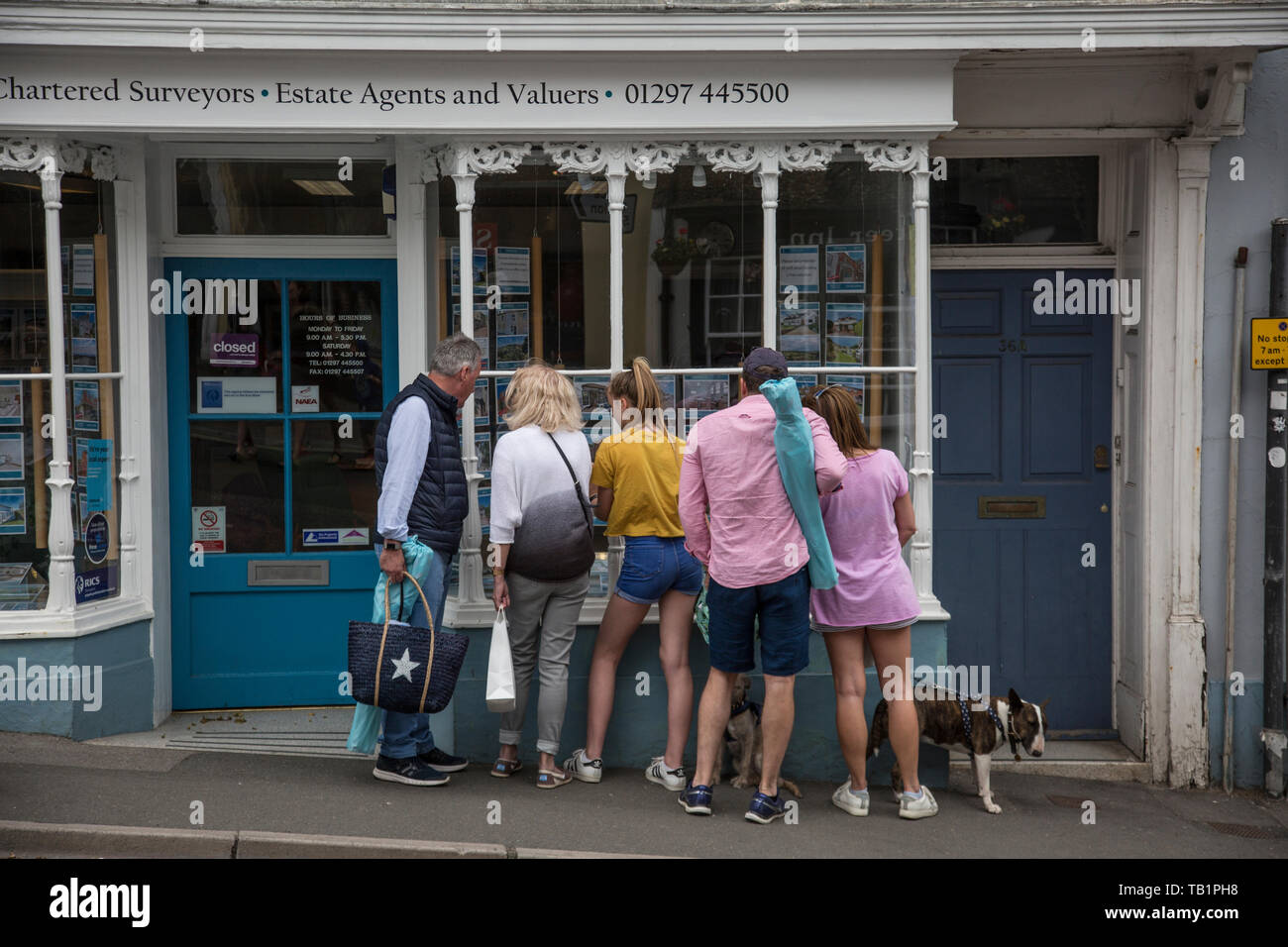 Famiglia guardando le proprietà per la vendita pubblicizzato in un agente immobiliare finestra nel West Dorset, England, Regno Unito Foto Stock
