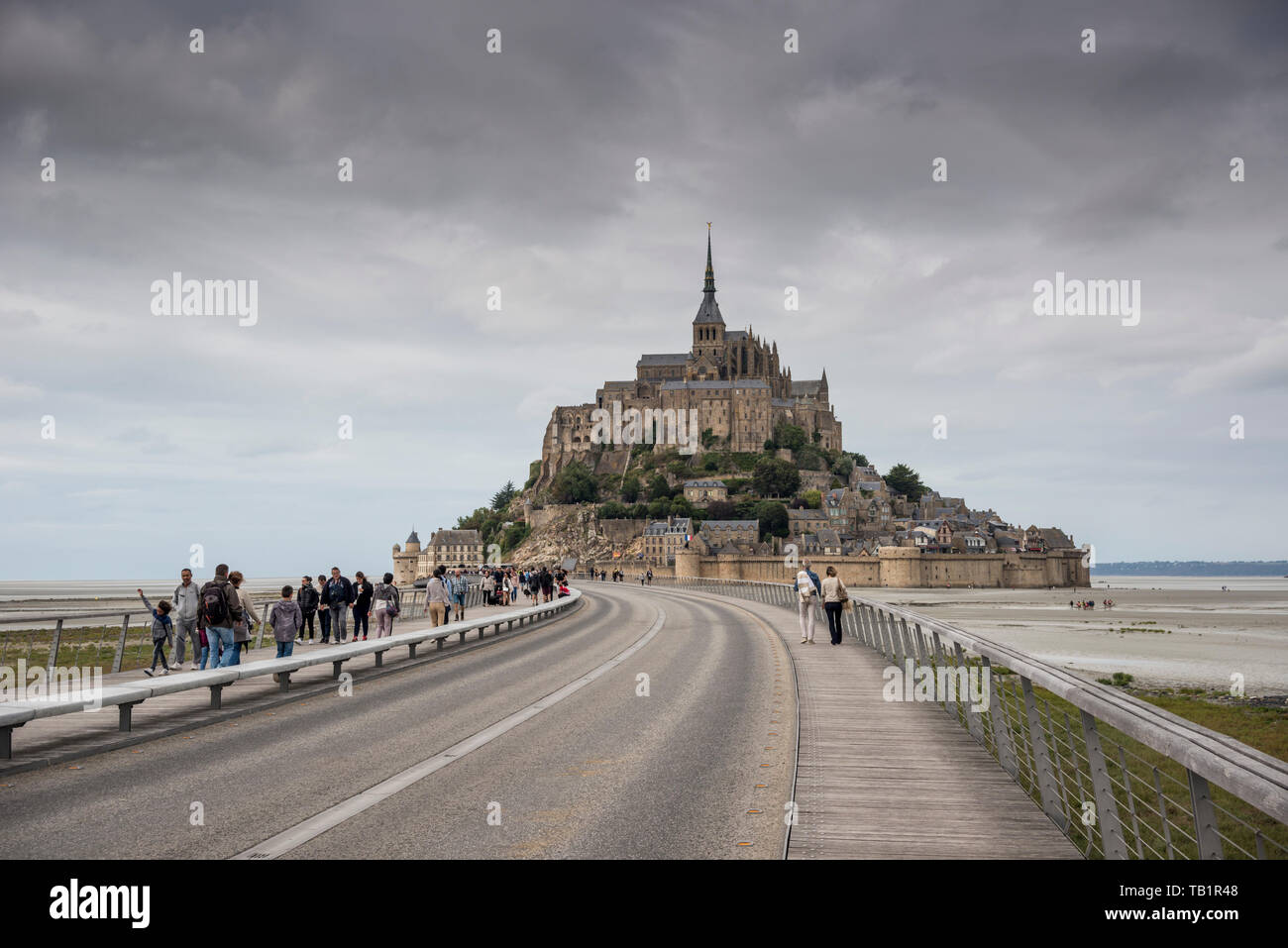 I turisti a piedi e da Le Mont Saint Michel, al di sopra di nuova costruzione passerella Ponte, Manche, Normandia, Francia Foto Stock