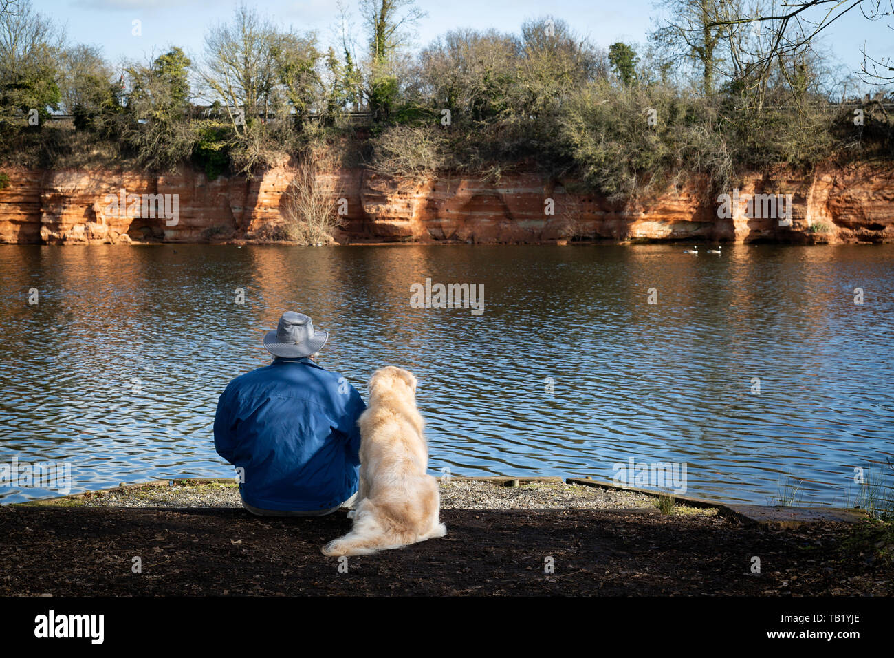 Uomo e cane rilassante da un laghetto Foto Stock