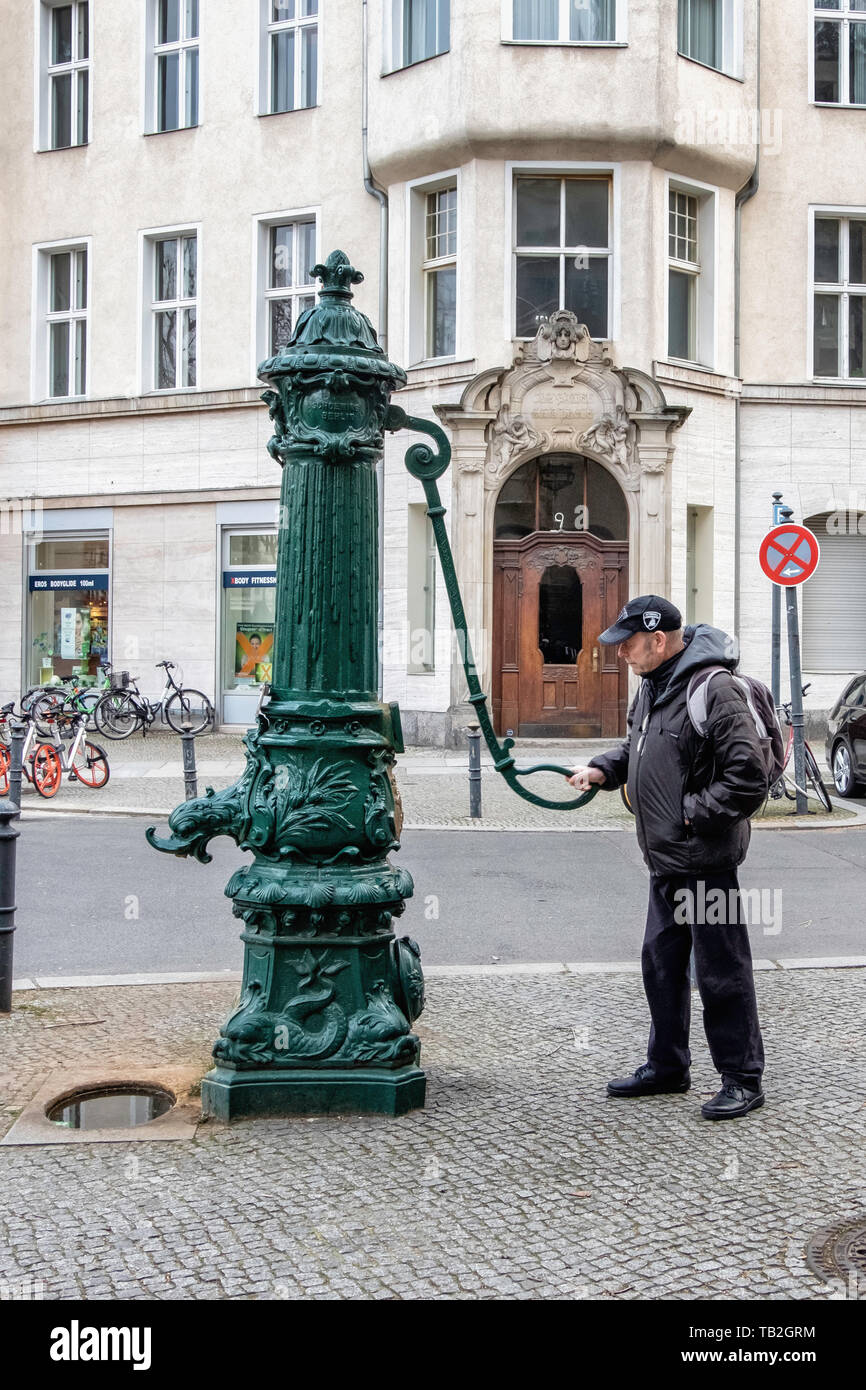 Schöneberg-Berlin. Uomo anziano con ornati vecchia pompa acqua di fronte all edificio storico su Viktoria Luise Platz Foto Stock