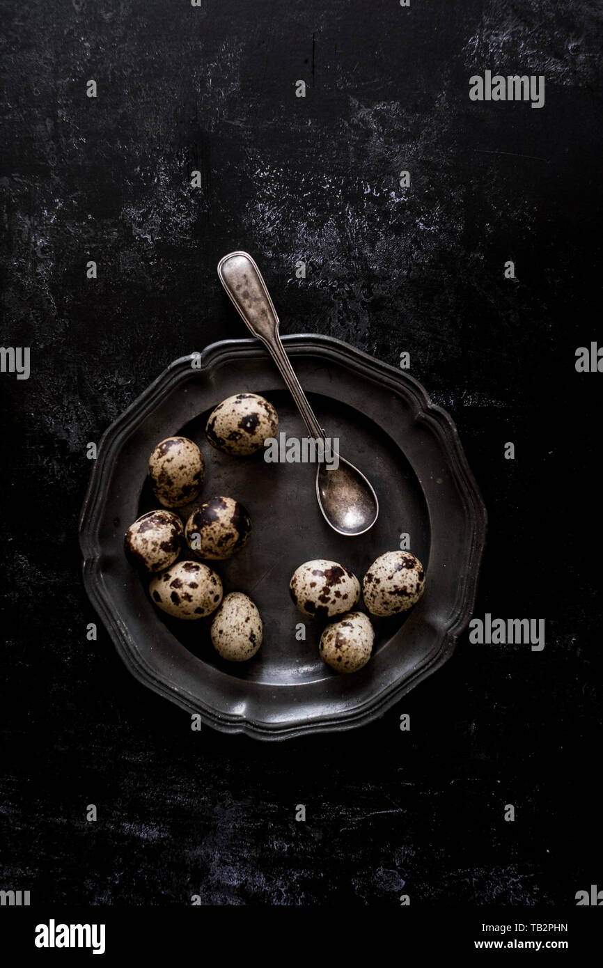 Una piastra in peltro con piccole macchiato di quaglia uova e un cucchiaio. Foto Stock