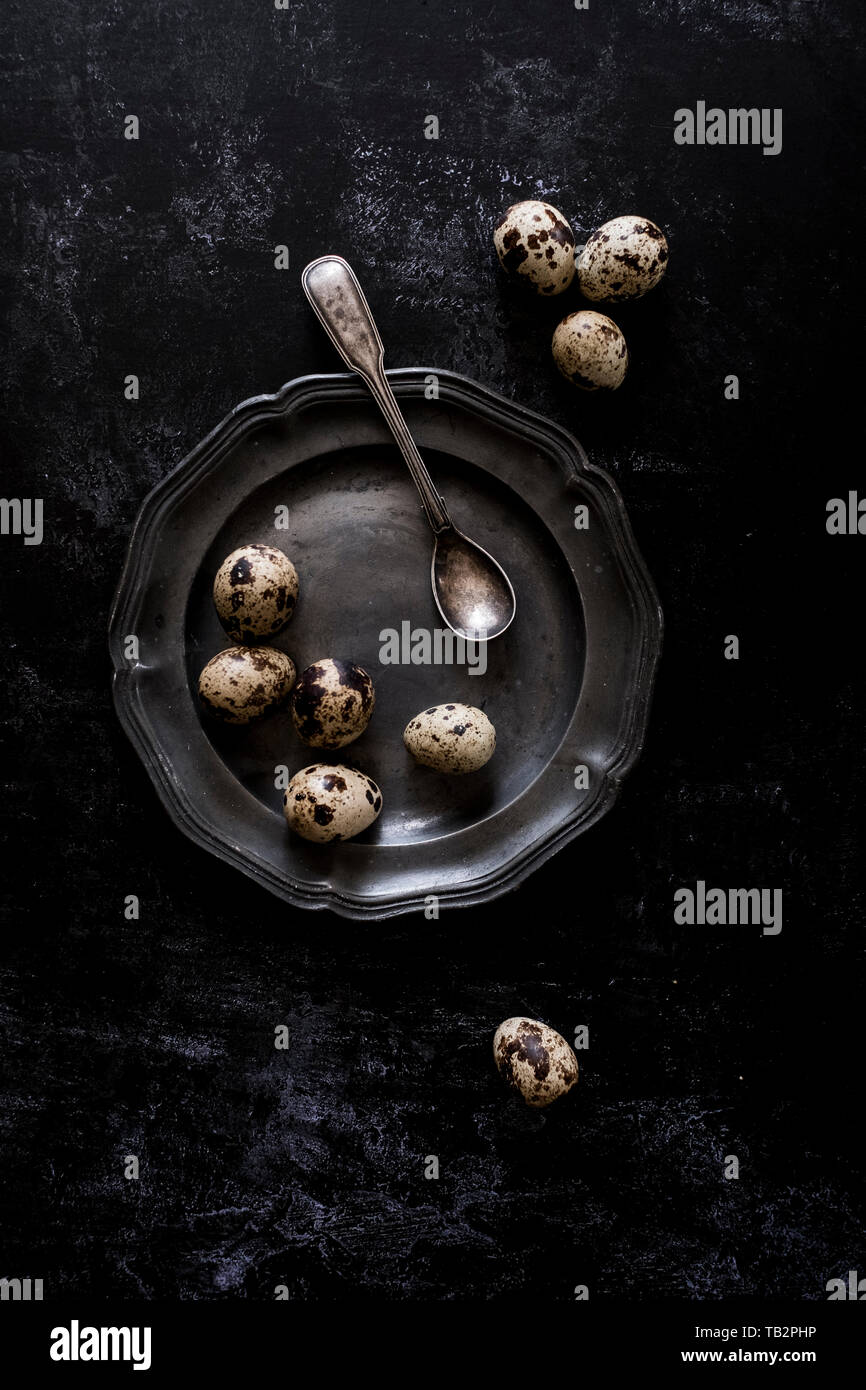 Una piastra in peltro con piccole macchiato di quaglia uova e un cucchiaio. Foto Stock