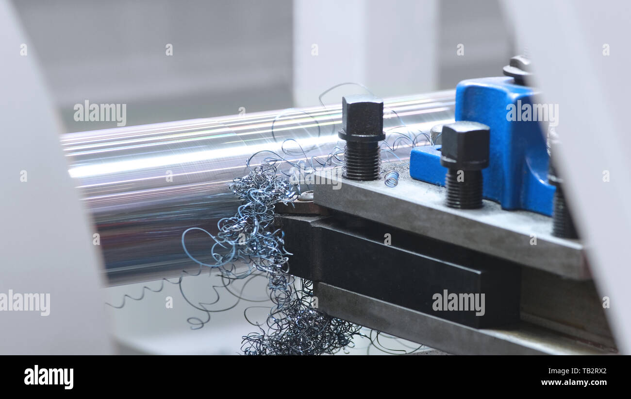 Industria metallurgica: taglio acciaio albero in metallo la lavorazione su macchina tornio in officina. Messa a fuoco selettiva sull'attrezzo Foto Stock