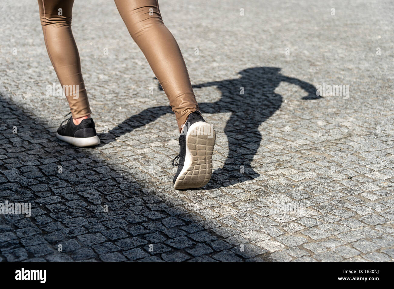 Close up di scarpe da corsa con sfondo ombra su una strada acciottolata Foto Stock