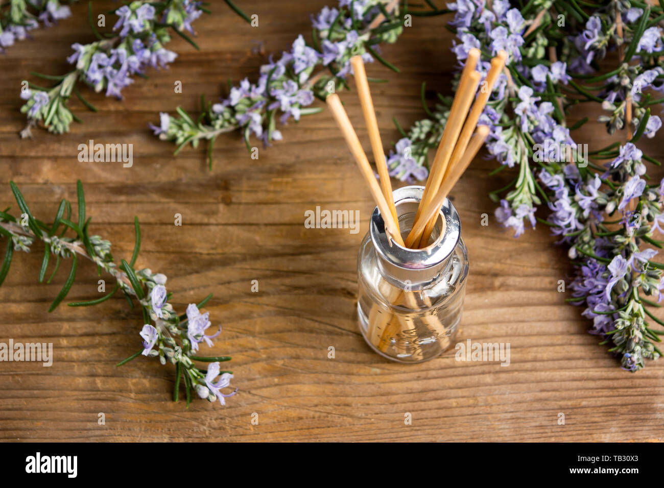 Aria di rosmarino olio rinfrescante in una bottiglia con rami di fiori Foto Stock