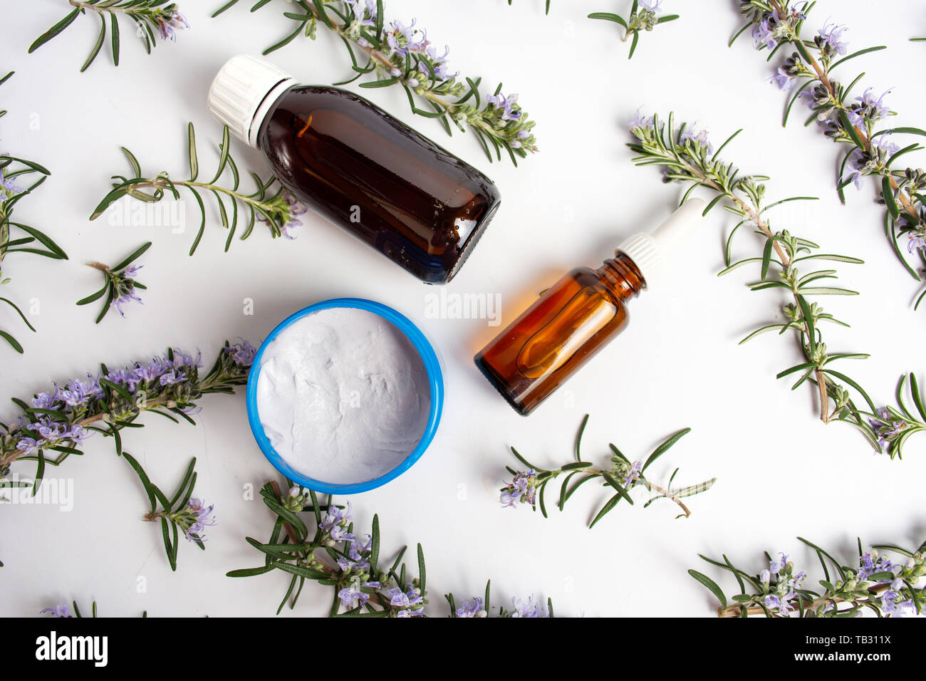 Olio di rosmarino e crema con rami di fiori vista superiore Foto Stock