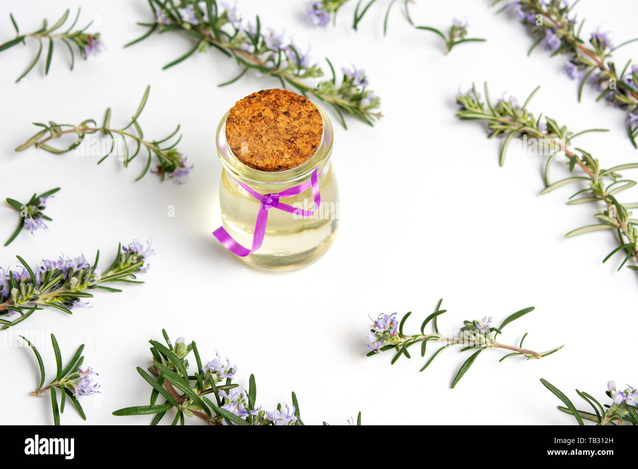 Olio di rosmarino in una bottiglia con rami di fiori vista superiore Foto Stock