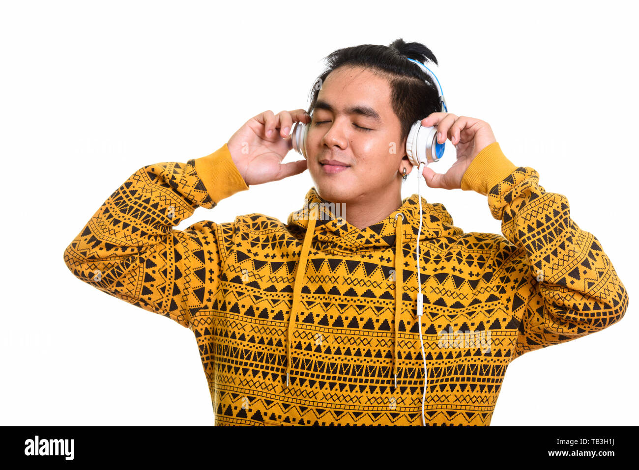 Felice uomo asiatico sorridente mentre si ascolta la musica con gli occhi chiudi Foto Stock