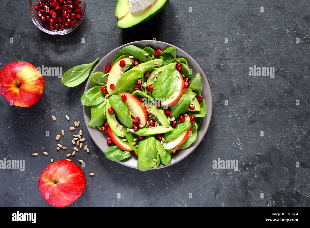 Fresca insalata di avocado con spinaci, Apple, melograno e semi di girasole su sfondo scuro. Vista da sopra con copia spazio. Foto Stock