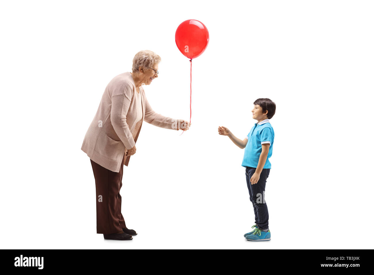 Lunghezza piena ripresa del profilo di una nonna dando un palloncino rosso per un nipote isolati su sfondo bianco Foto Stock