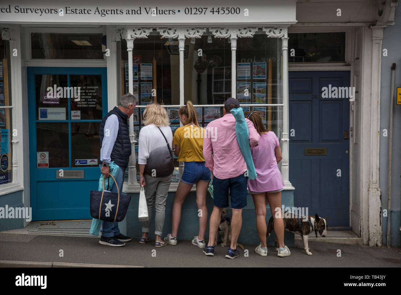 Famiglia guardando le proprietà per la vendita pubblicizzato in un agente immobiliare finestra nel West Dorset, England, Regno Unito Foto Stock