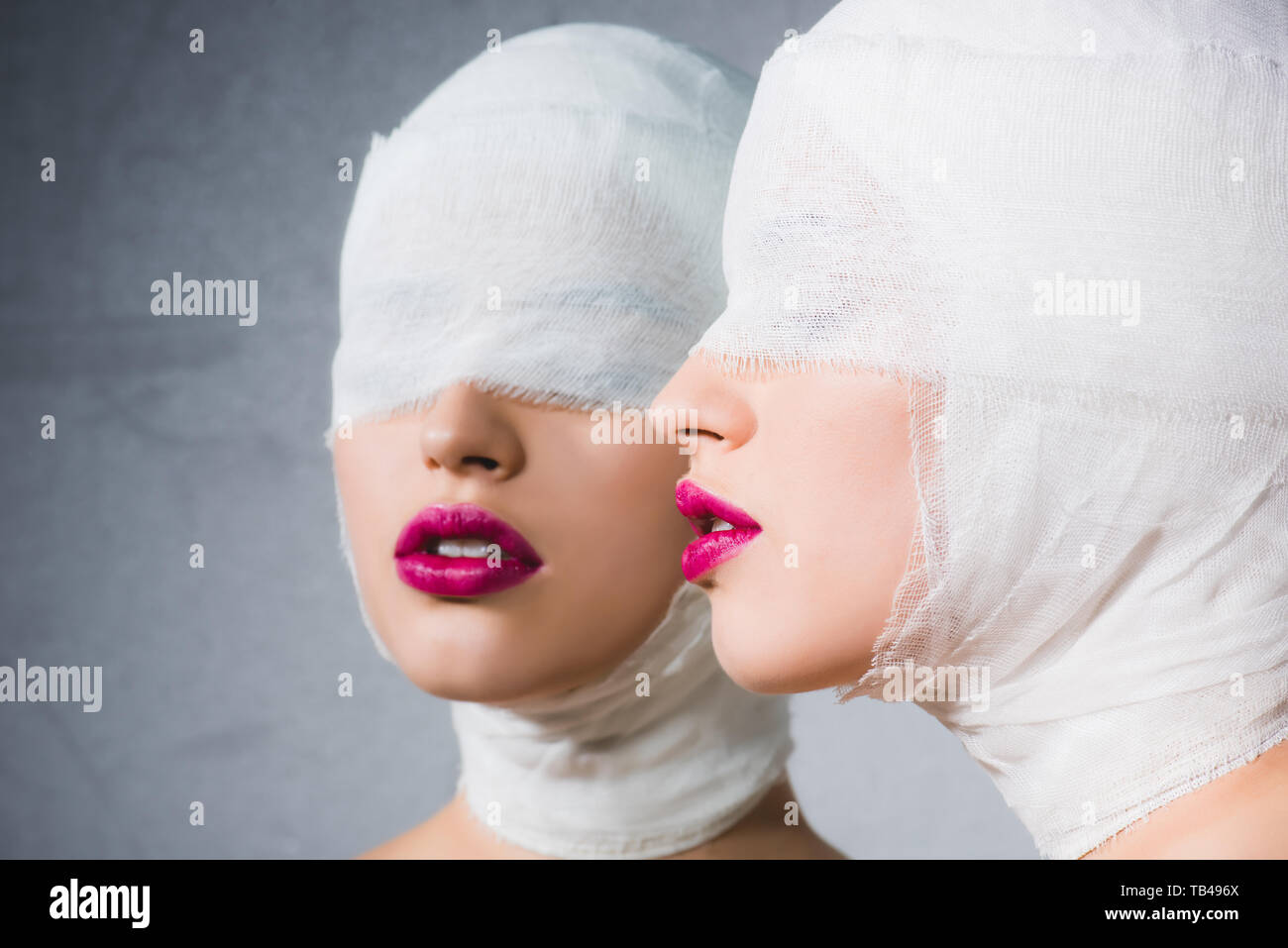 Un riflesso speculare della donna con la testa fasciata e gli occhi su grigio Foto Stock