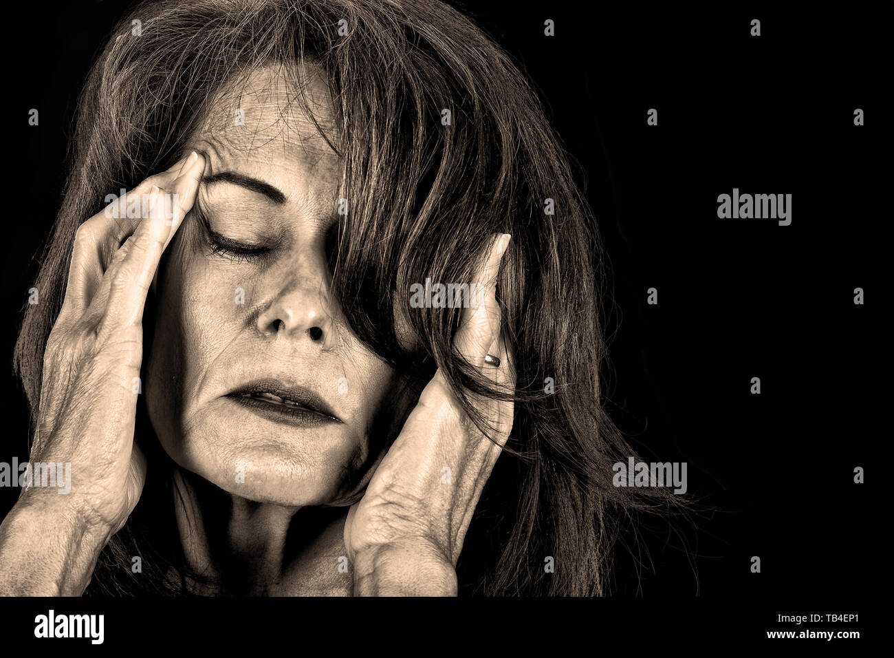 Immagine in bianco e nero di una donna matura tenendo le mani sulla testa del dolore. Foto Stock