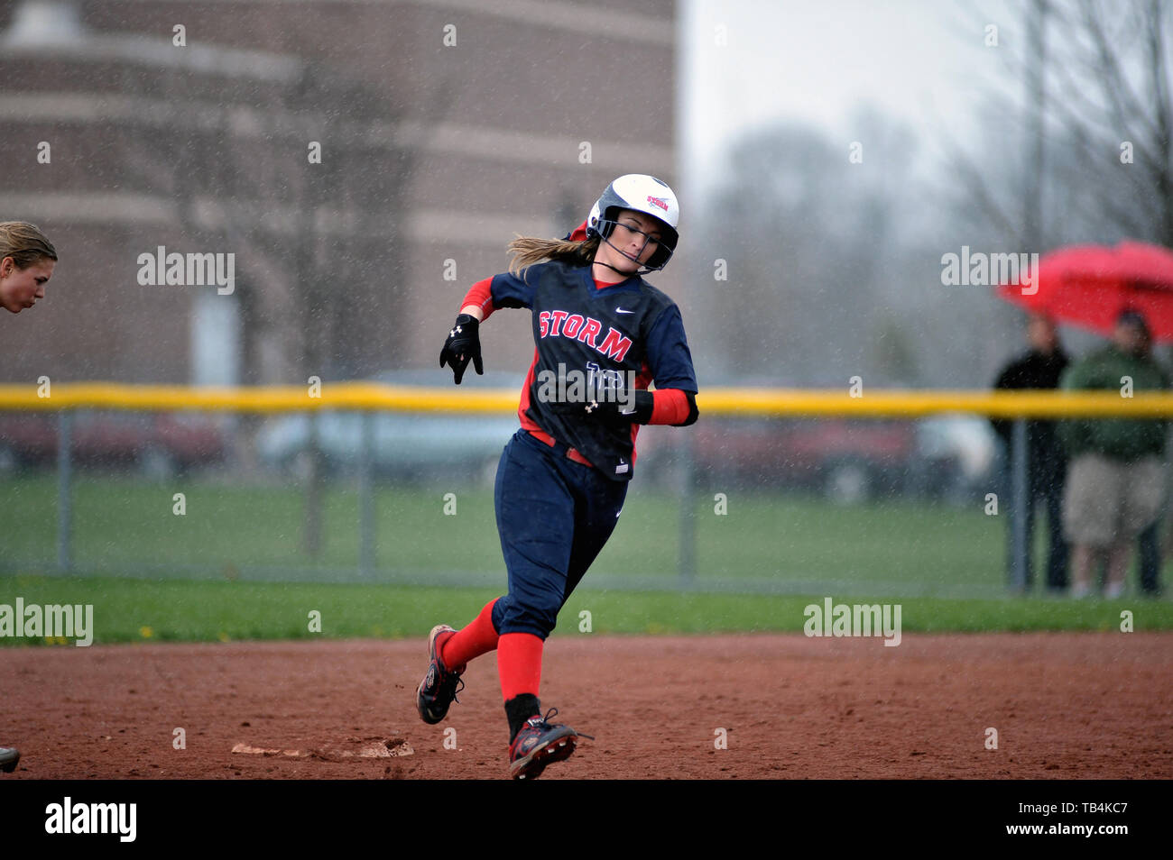 Pastella arrotondamento seconda base durante la sua esecuzione domestica di trotto durante una high school softball gioco. Stati Uniti d'America. Foto Stock