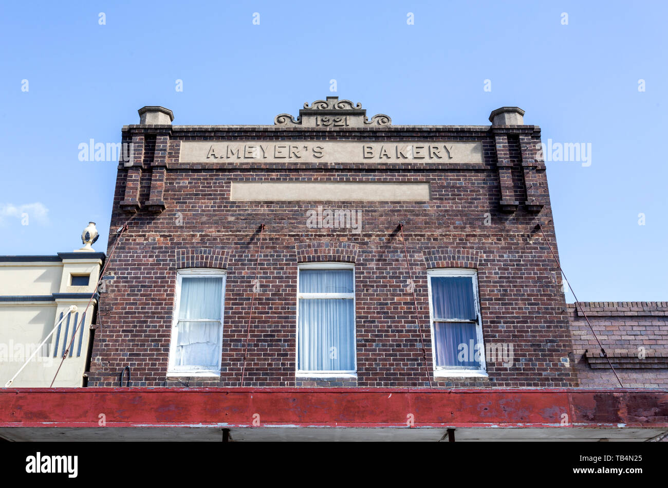 Facciata di un 1921 mattone edificio commerciale con alto parapetto e reso frontone decorato, nella cittadina rurale di Glen Innes, Nuovo Galles del Sud, Austra Foto Stock